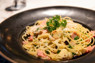 Spaghetti with dried chili, garlic, olive oil and ham with parmesan cheese on top.