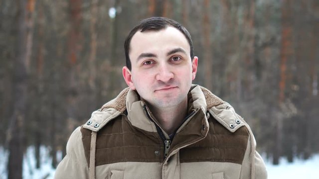 Portrait of young man who winking at camera in winter forest