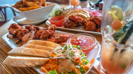 Grilled chicken wings, baked western potatoes, sweet Chinese souse and fresh salad in outdoor restaurant