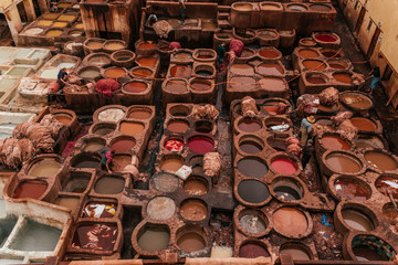 Obraz premium View inside of old medina in Fes, a traditional and old tannery with workers working making methods of leather in the city Fes, Morocco, in april of 2019. 