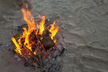 bright yellow bonfire on gray sand close up in the evening