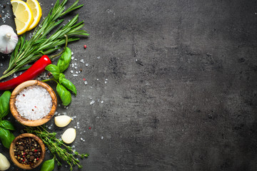 Selection of spices and herbs on dark stone table.