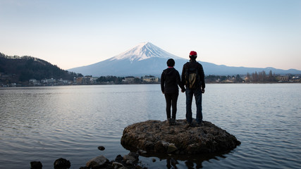 A couple enjoying Sunrise view of Mt Fuji on the northern shore of Lake Kawaguchiko in Japan