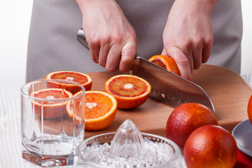 young woman in a gray apron cuts blood orange