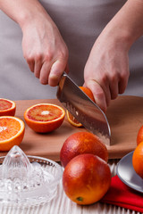young woman in a gray apron cuts blood orange