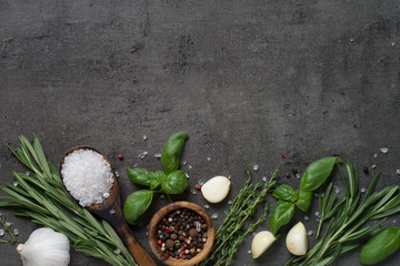 Selection of spices and herbs on dark stone table.