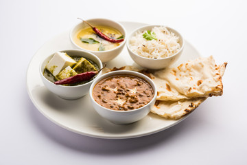 Indian vegetarian  platter / Thali having Palak paneer butter masala, dal makhani, flat bread or naan and rice served in a white plate