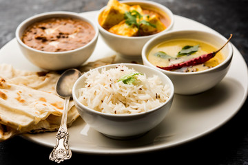 Indian vegetarian  platter / Thali having Palak paneer butter masala, dal makhani, flat bread or naan and rice served in a white plate