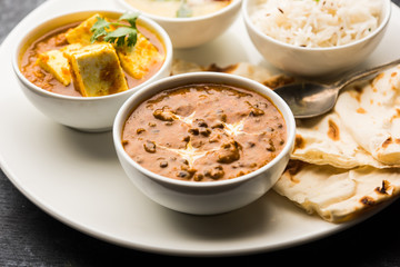 Indian vegetarian  platter / Thali having Palak paneer butter masala, dal makhani, flat bread or naan and rice served in a white plate