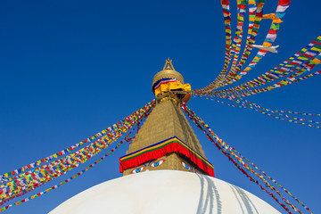 Buddhist Tibetan stupa Bodnath in Kathmandu with multicolored prayer flags against a clean blue sky