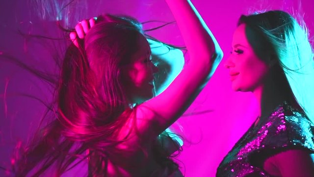 Hot model girls dancing in UV neon lights. Disco party. Sexy young women with perfect slim bodies dancing. Night life. Slow Motion 4K UHD video footage. 3840X2160