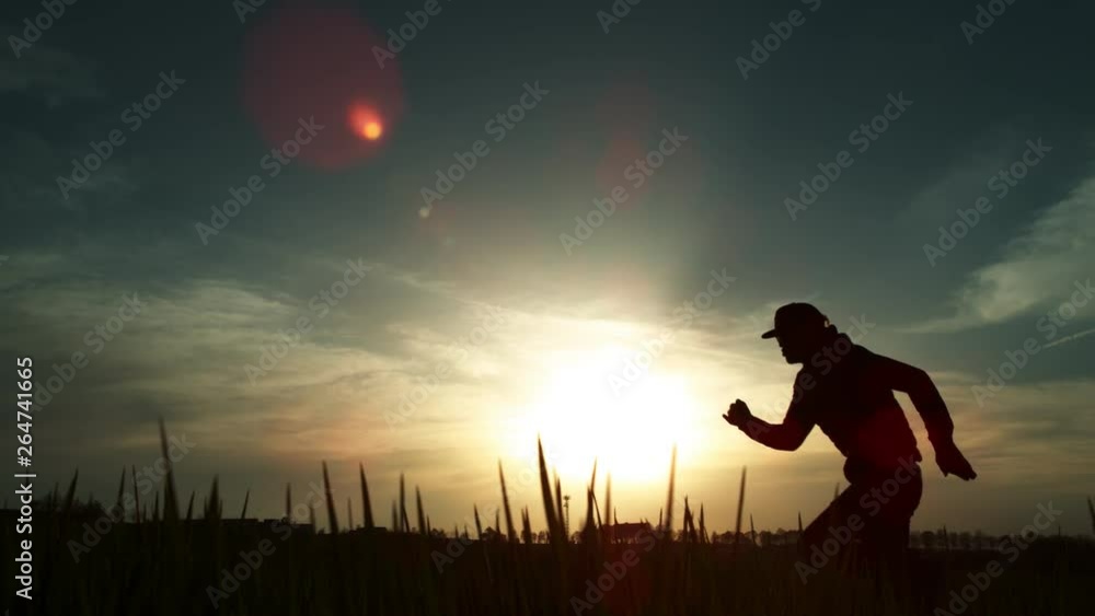 Wall mural Super slow motion of running man silhouette in sunset. 