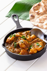 Close up traditional Indian butter chicken curry and lemon served with chapati bread on iron cast.