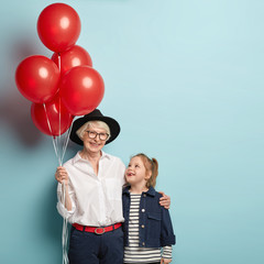 Vertical image of glad granny and small female child embrace, have nice relationships, celebrate...