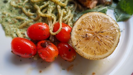 Closeup of grilled salmon pasta with grilled yellow lemon and red small tomatoes. Selected focus....