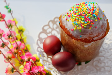 Easter cake in white glaze and sprinkling of colored sweet balls. Painted Easter eggs.