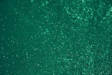 Vintage green background. Rough painted wall of emerald color. Imperfect plane of virid colored. Uneven old decorative toned backdrop of green tint. Texture of emerald hue. Ornamental stony surface.