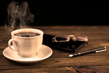 Cup of coffee, smartphone, glasses, fountain pen on wooden table background. lunch break. coffee-break,