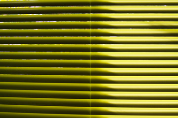 Obraz premium Yellow lamellas of vertical blind shining in natural sun light