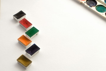 Bright colorful watercolor paints on a white background. Close-up watercolor tray. Flat lay, top view, copy space. School and creativity concept