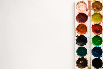 Bright colorful watercolor paints on a white background. Close-up watercolor tray. Flat lay, top view, copy space. School and creativity concept