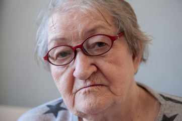 Elderly woman with beautiful face in wrinkles with gray hair with glasses. Closeup portrait. Grandmother Retired waiting for social assistance.