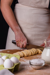 young woman in apron kneading dough on board
