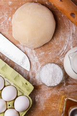 young woman in apron kneading dough on board