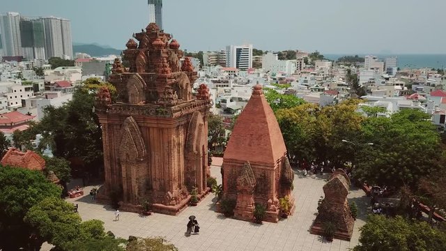 Ancient historic important red ruin Po Nagar temple tower Vietnam landmark Nha Trang Aerial approach.   structure complex. Important tourist religious. Beautiful sunny cityscape old modern houses