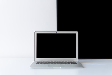 Open laptop with black frame behind on the desk with white background