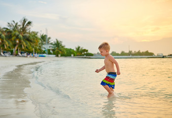 Three year old toddler boy on beach at sunset