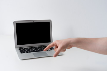 Open laptop with finger pointing on the desk with white background