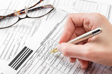 Woman filling health insurance claim form. Close up.
