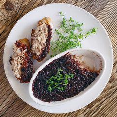 a plate with bowl of pork rillettes under red onion confiture and sandwiches with the pork decorated with thyme on wooden top 