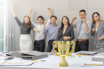 Selective focus of trophy with blurred success group of business people team meeting working in office