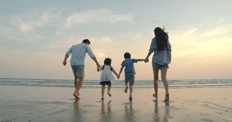 SLOW MOTION - Asian family running on the beach at sunset with happy emotion. Family, Holiday and Travel concept. Back Rear View. - Powered by Adobe