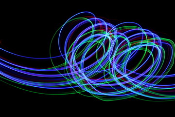 Long exposure, light painting photography.  Vibrant neon streaks of colour against a black...