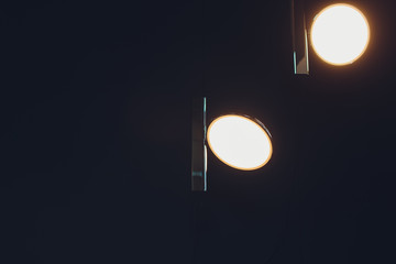Obraz na płótnie Canvas Two incadescent light bulbs in an industrial lamp. Dark environment. Concept of idea. Copy space on the left.