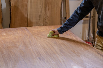Craftsman carpenter working in his studio giving oil to a chestnut wood board.