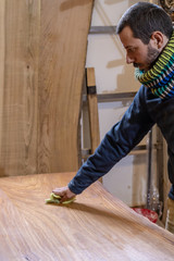 Craftsman carpenter working in his studio giving oil to a chestnut wood board.