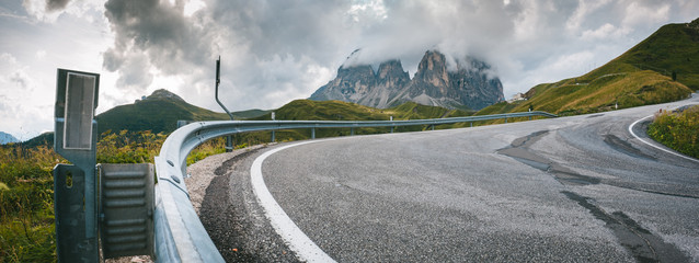 Serpentyna na asfaltowej włoskiej górskiej drodze z barierami i szczytami gór w tle © Tomasz