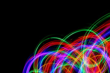 Long exposure, light painting photography. Multi color streaks and swirls of red, green and blue light against a black background.