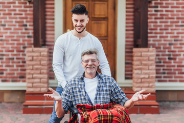 The son  walking with his father on wheelchair near nursing home!