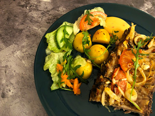 Delicious, juicy spare ribs with fried potatoes, vegetables, mixed salad and sauces on metallic background.