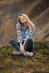 A young woman sits next to a cliff.