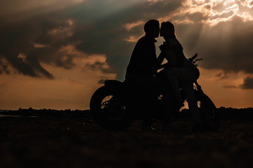 Obraz na płótnie Canvas Couple on a motorbike at sunset