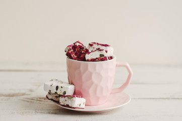 Hibiscus nougat in a pink coffee cup on wooden table. Turkish delight. Lebanese sweets. Arabic dessert