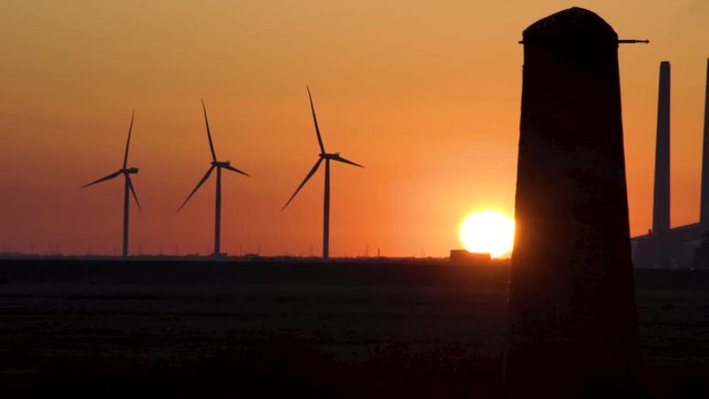 Wind turbines and coal burning power plant smooth tripod pan from green energy to fossil fuel climate concept