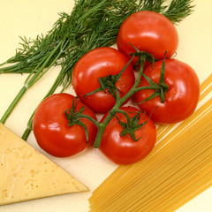 On a yellow background, red tomatoes on a green branch, a slice of yellow cheese, spaghetti pasta, dill twigs. Concept - healthy food. Top view