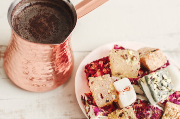 Turkish coffee in a brass cezve and a plate with assorted lebanese sweets. Turkish delight